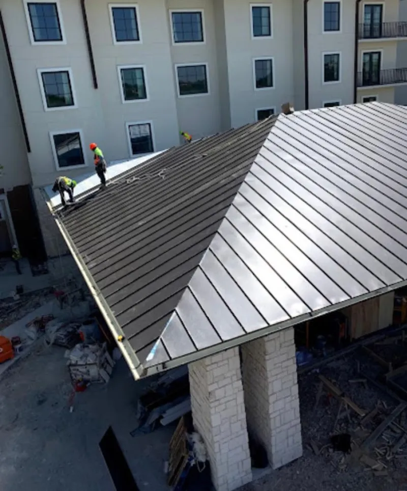 Crew installing standing seam metal roof panels on a commercial project in Columbia